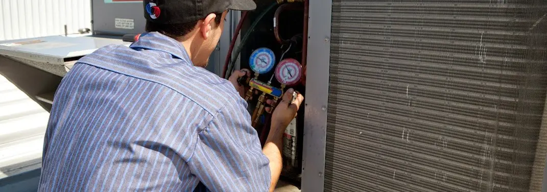 HVAC technician servicing a condenser unit in Altoona